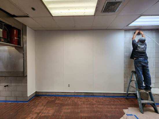 Worker installing wall panels in kitchen